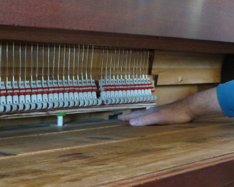 Hand feeling for glue drips and debris on backrail of keybed.